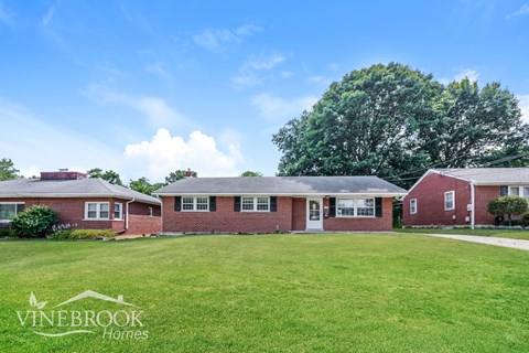 a brick house with a green lawn in front of it